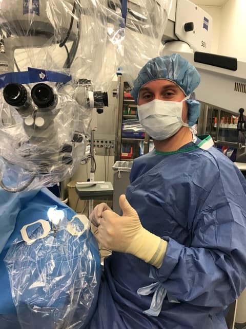 Cataract surgeon in scrubs standing in front of equipment